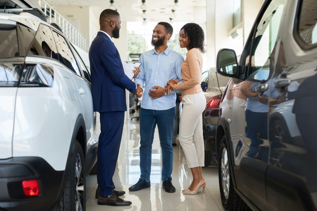 car-purchase-happy-customers-couple-handshaking-with-manager-in-auto-salon